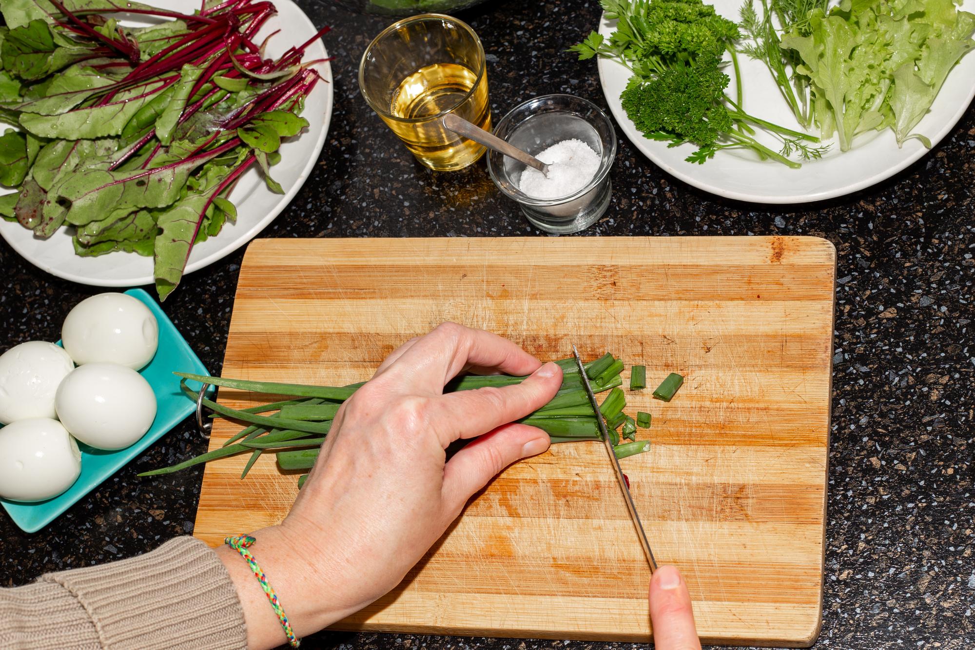 hands chopping herbs on cutting board